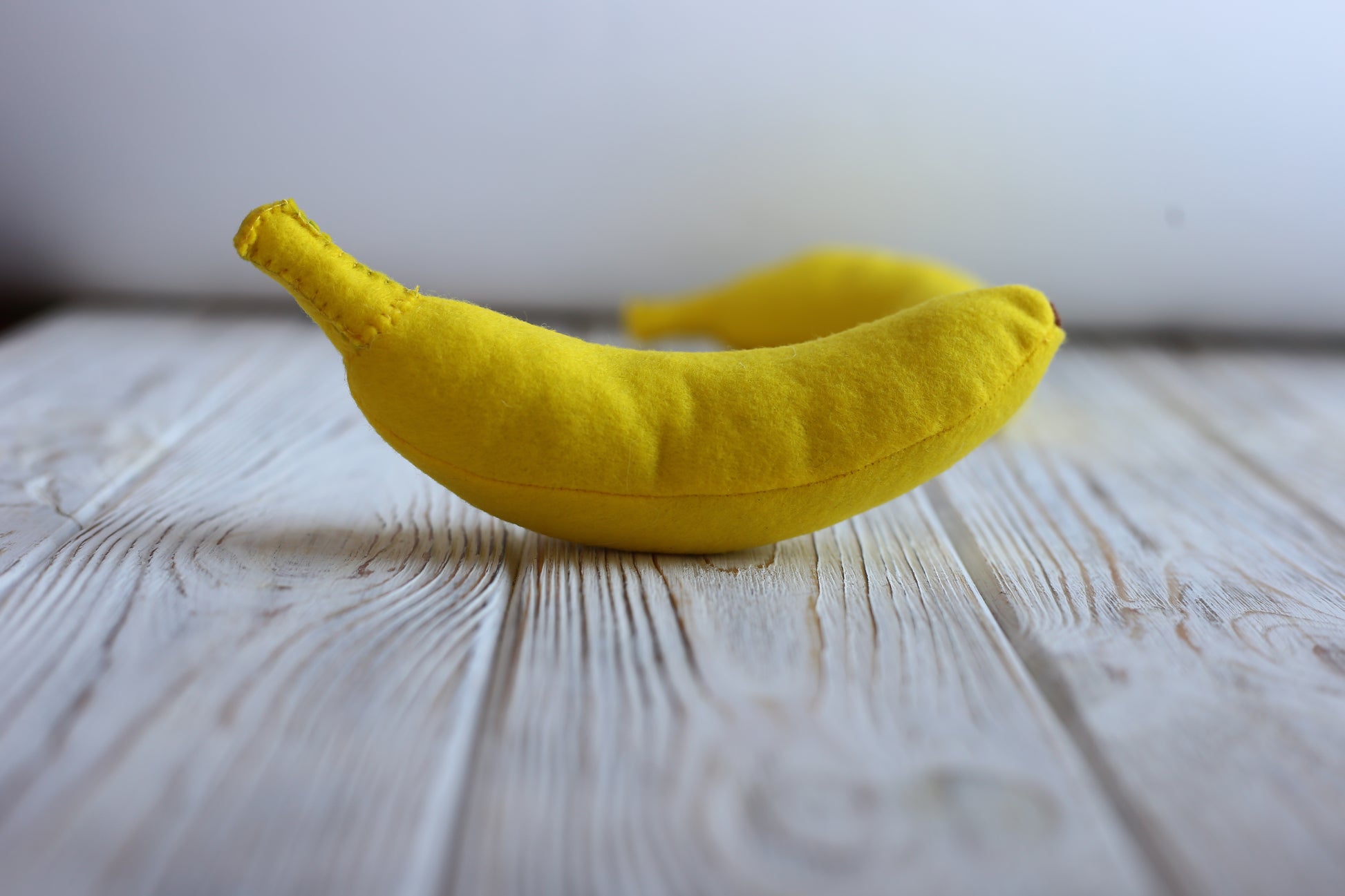 Yellow banana plush food toy on a wooden surface