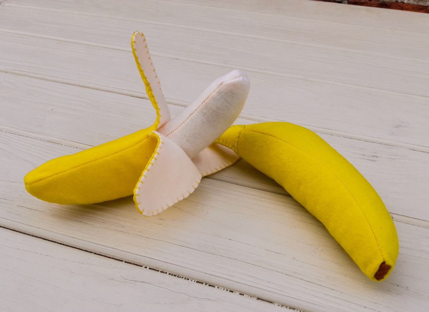 Plush food toy banana with a peel on a wooden surface