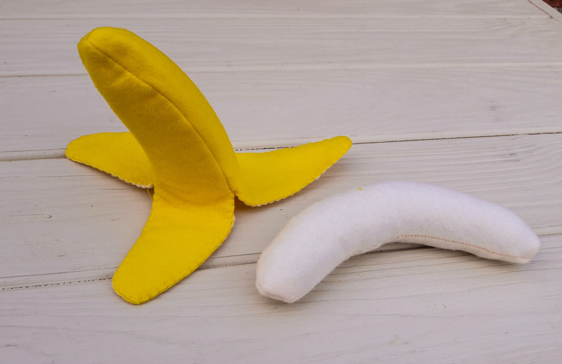 Yellow plush food toy banana on a wooden surface
