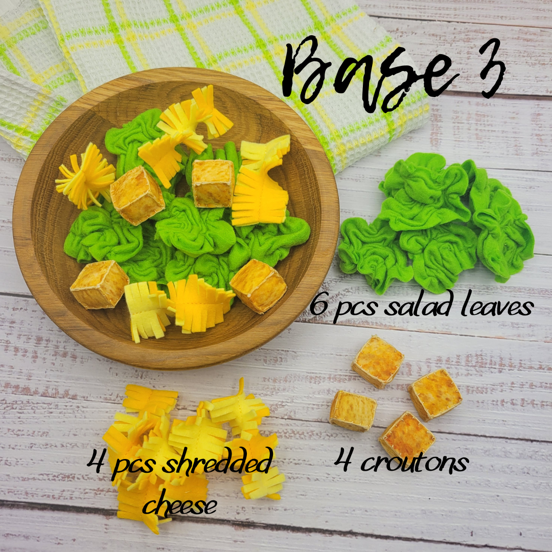 Wooden plate with green and yellow Caesar salad plush toy pieces labeled as salad leaves, shredded cheese, and croutons on a wooden surface.