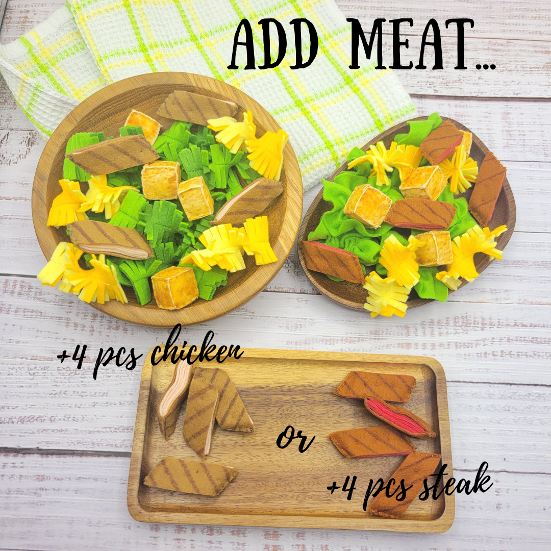 Wooden plates with caesar salad toy food items on a wooden surface, including chicken and steak pieces.