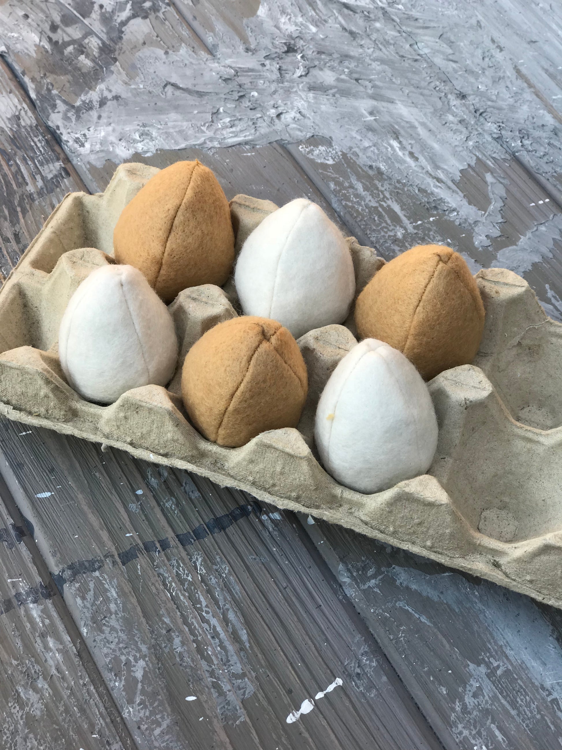 Egg carton with pretend play plush eggs on a textured surface