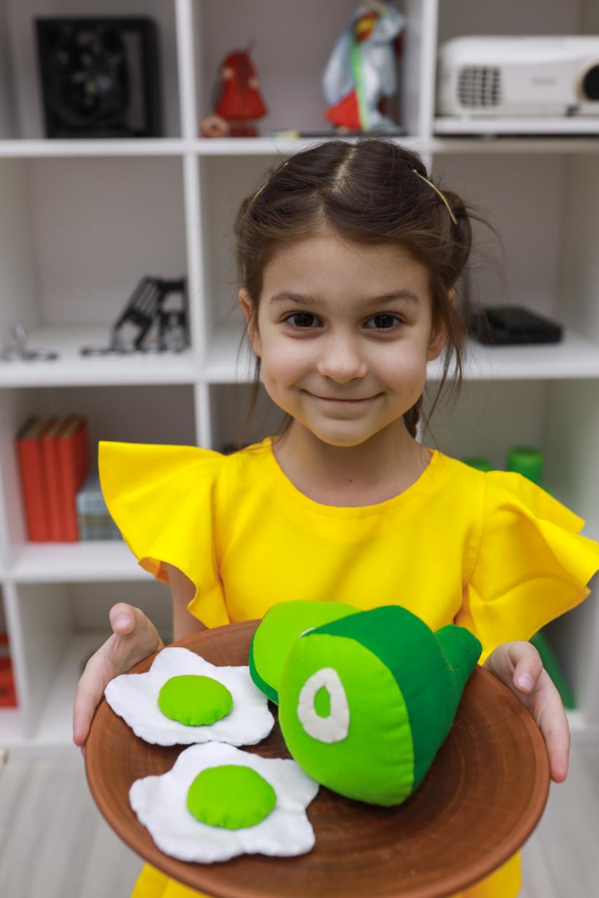 Little girl playing with pretend play food ham and eggs