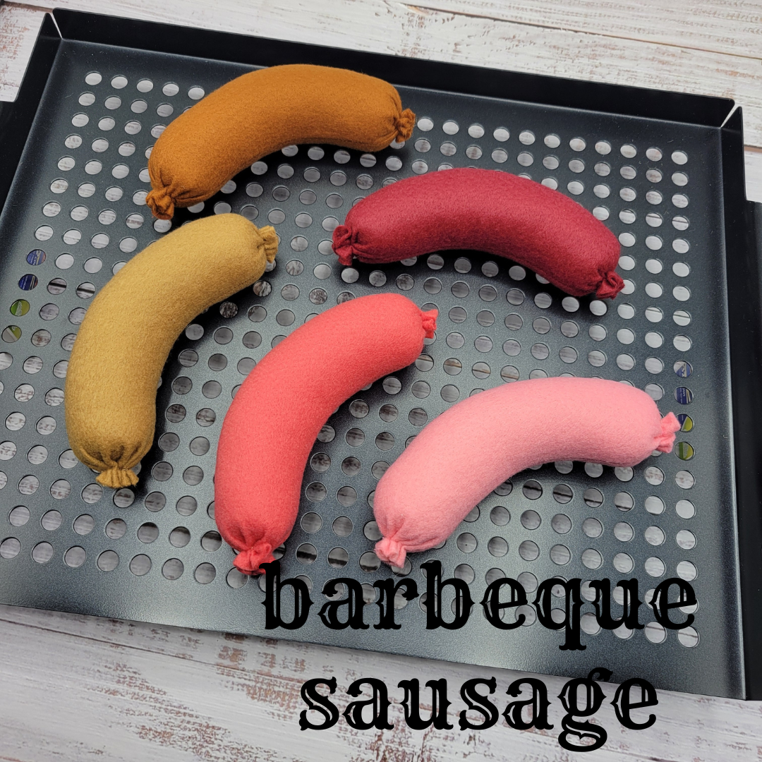 Four colored sausages plush pretend play toys on a perforated grill pan with 'barbeque sausage' text.