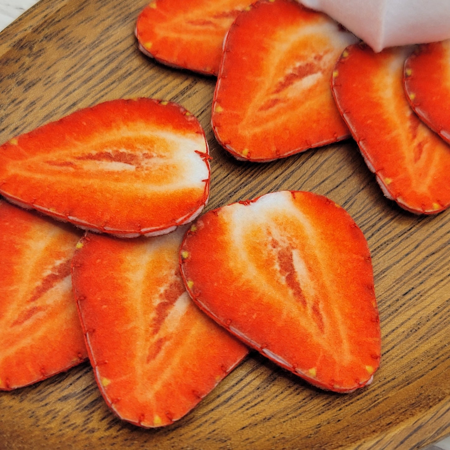 Sliced strawberries plush food toy on a wooden surface